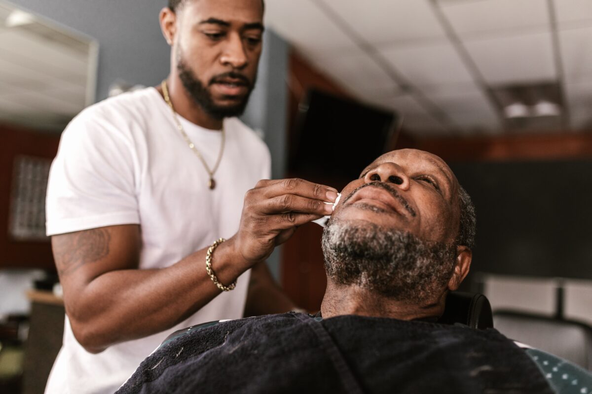 A barber is skillfully grooming an older man in a classic barbershop.